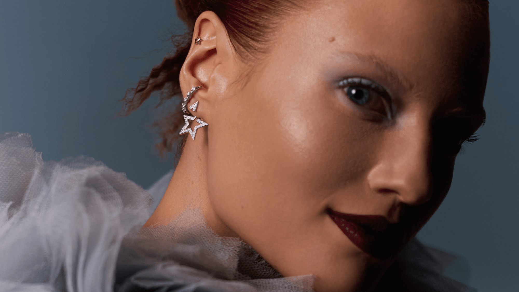 Une femme avec des boucle d'oreille en forme d'étoile regarde l'objectif