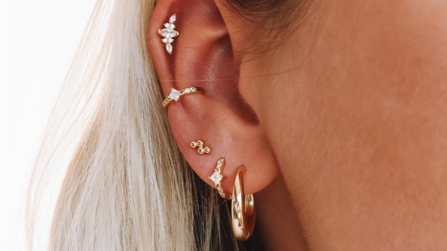 Oreille de femme avec plusieurs boucles et un piercing à l'hélix