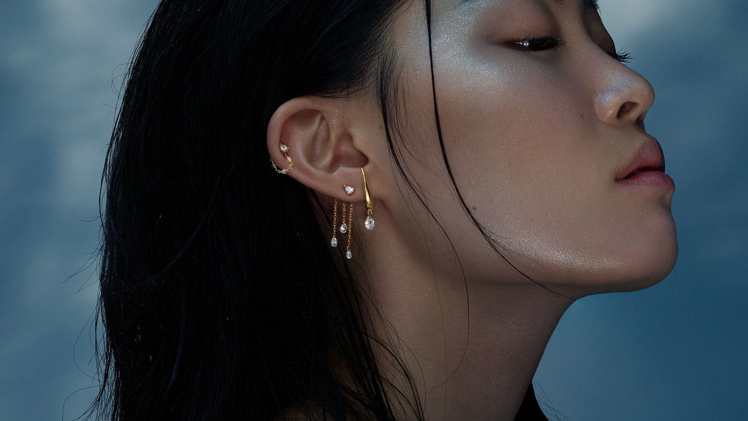 une femme de profil porte des bijoux en forme de goutte d'eau