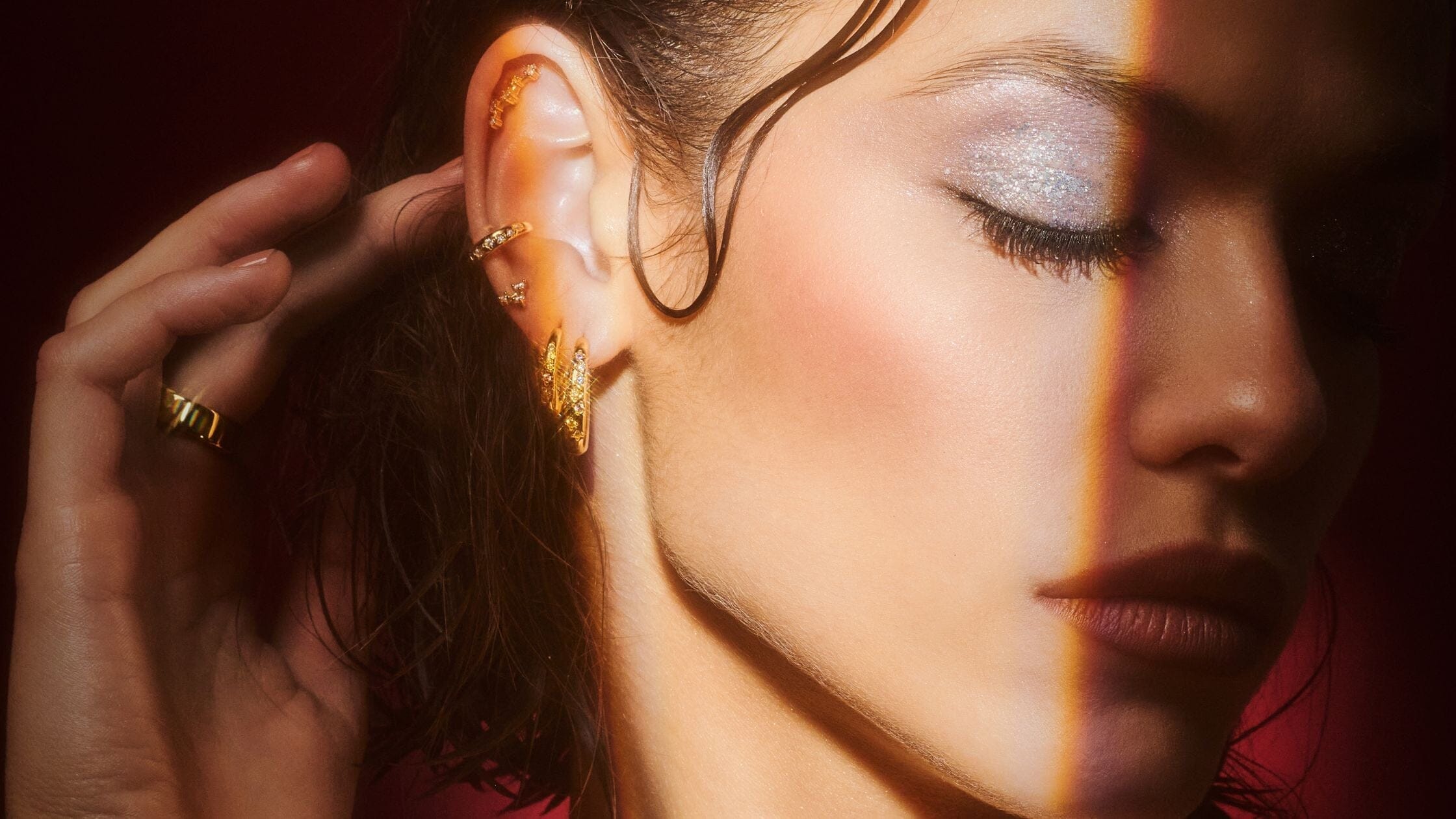 une femme portant des bijoux se met les cheveux derrière les oreilles