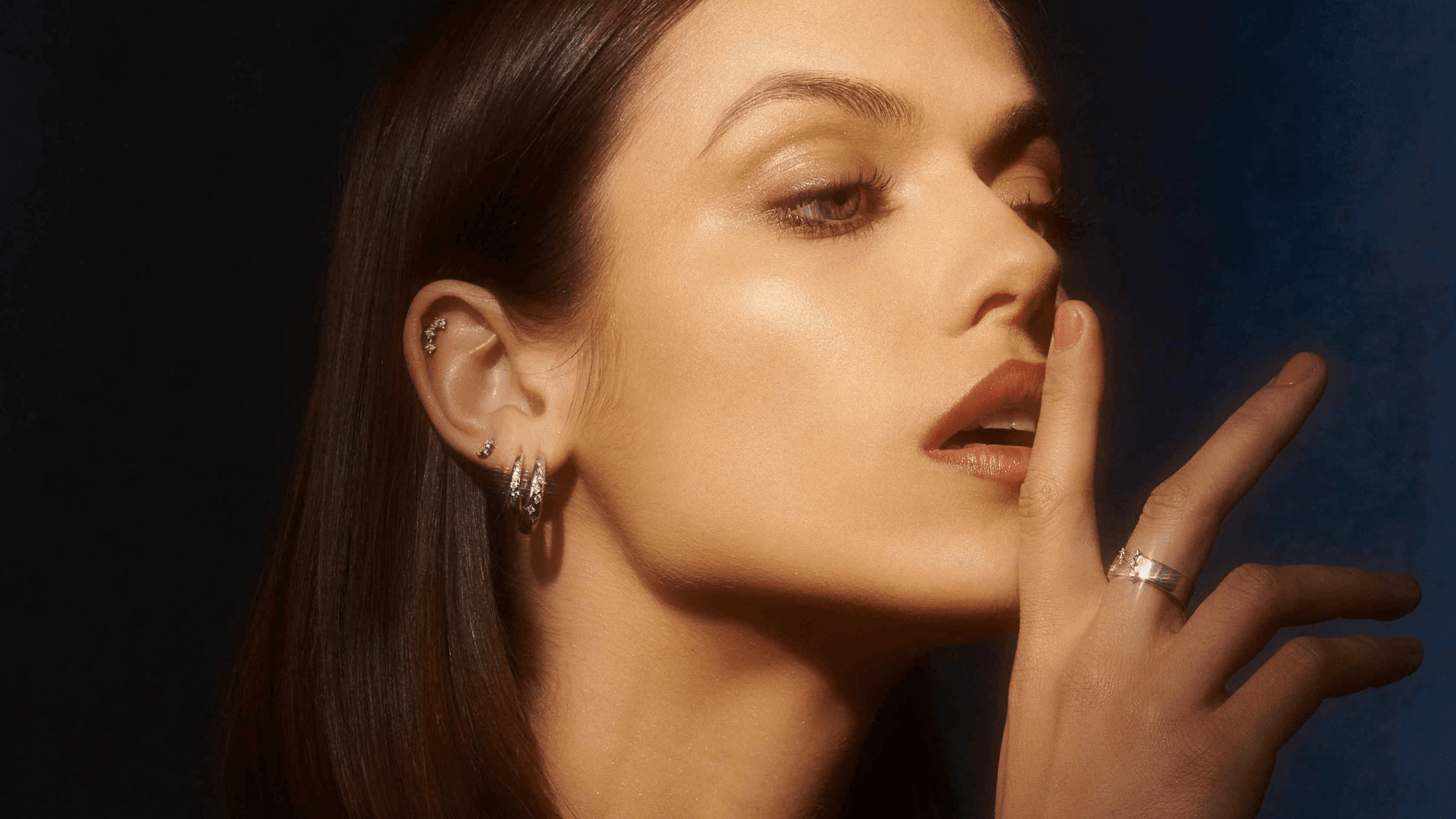 Femme souriante portant des boucles d'oreilles avec main proche du visage
