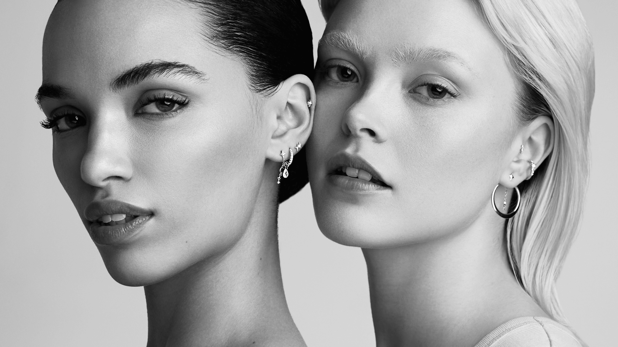 Une femme brune et une femme blonde sont côte à côte pour présenter leurs bijoux d'oreilles