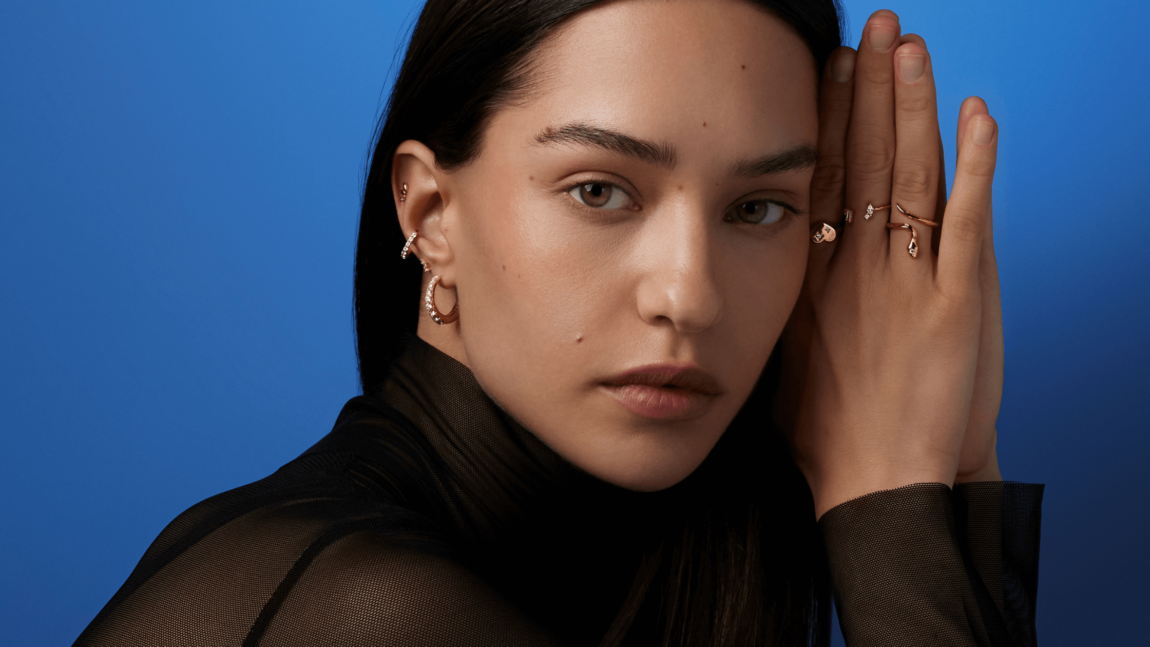 Une femme portant des bijoux regarde l'objectif